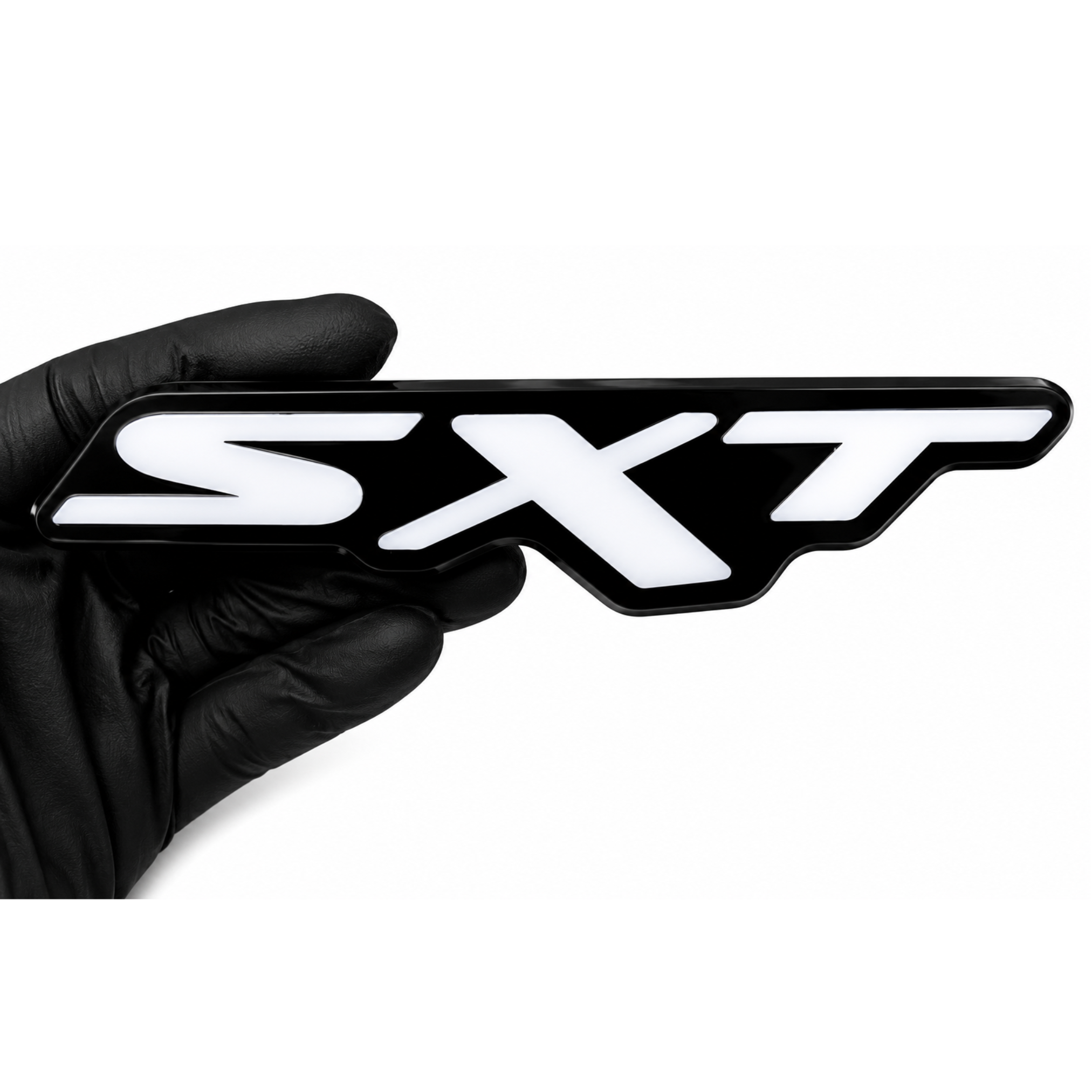 Dodge SXT RGB LED grille emblem with black housing and white face held by a gloved hand on a white background