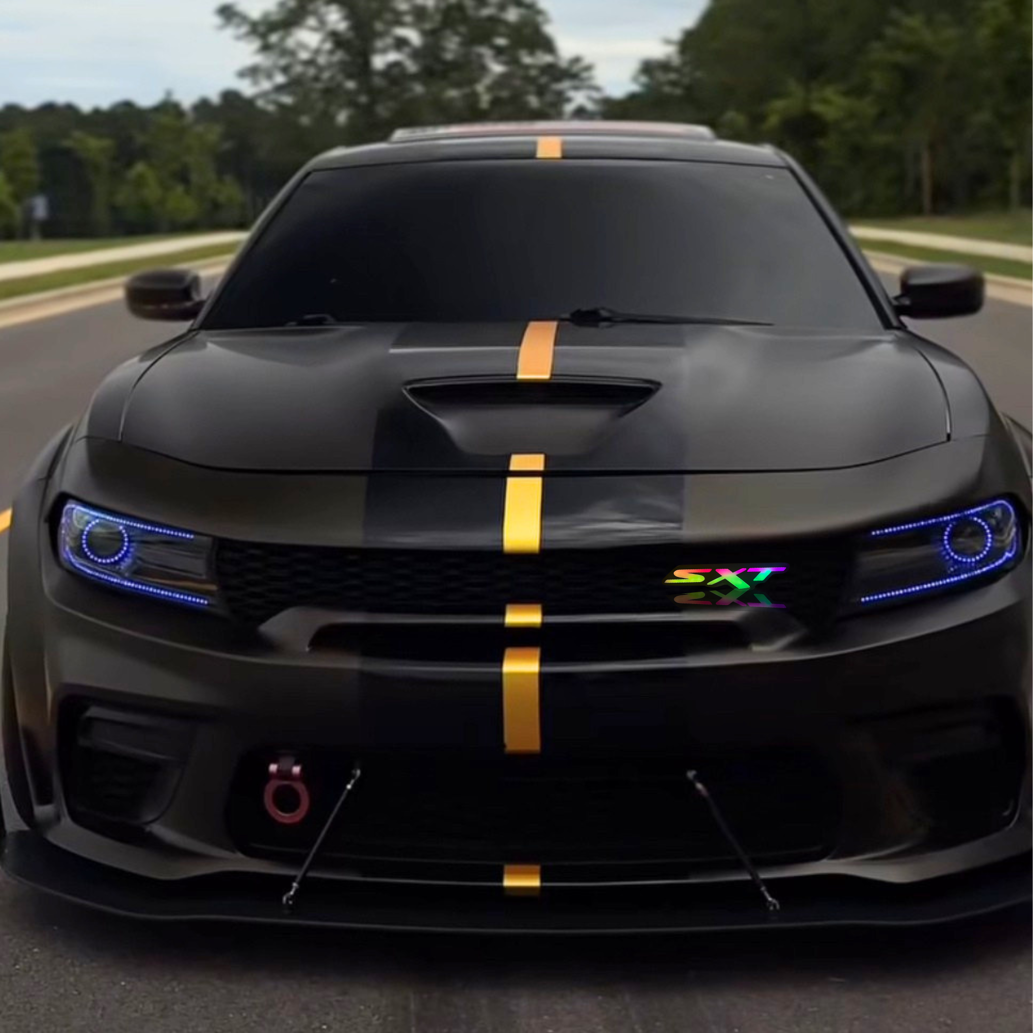 Dodge SXT RGB LED grille emblem shown installed on the grille of a black Dodge Charger with gold racing stripe.