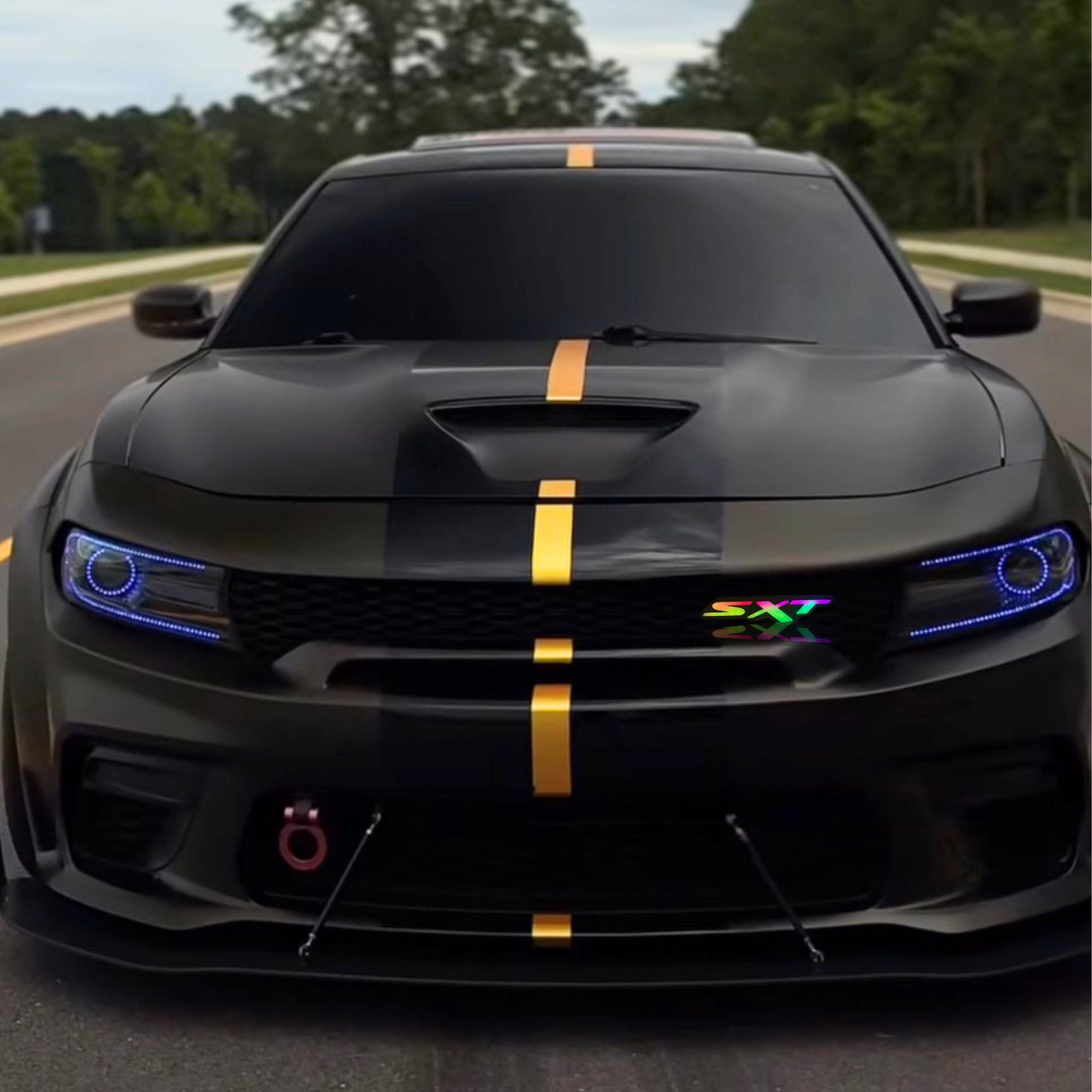 Dodge SXT RGB LED grille emblem shown installed on the grille of a black Dodge Charger with gold racing stripe.