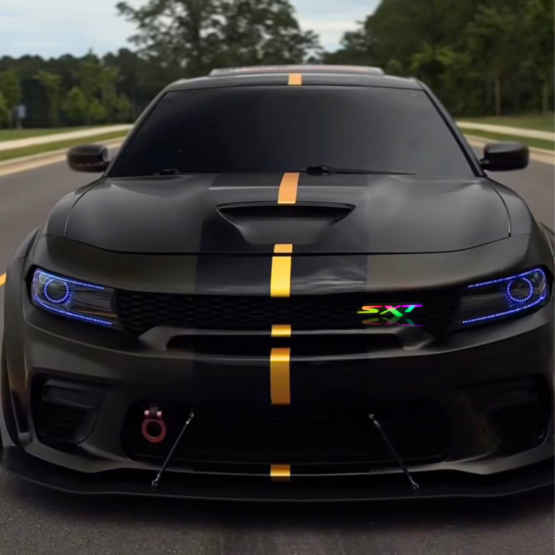 Dodge SXT RGB LED grille emblem shown installed on the grille of a black Dodge Charger with gold racing stripe.