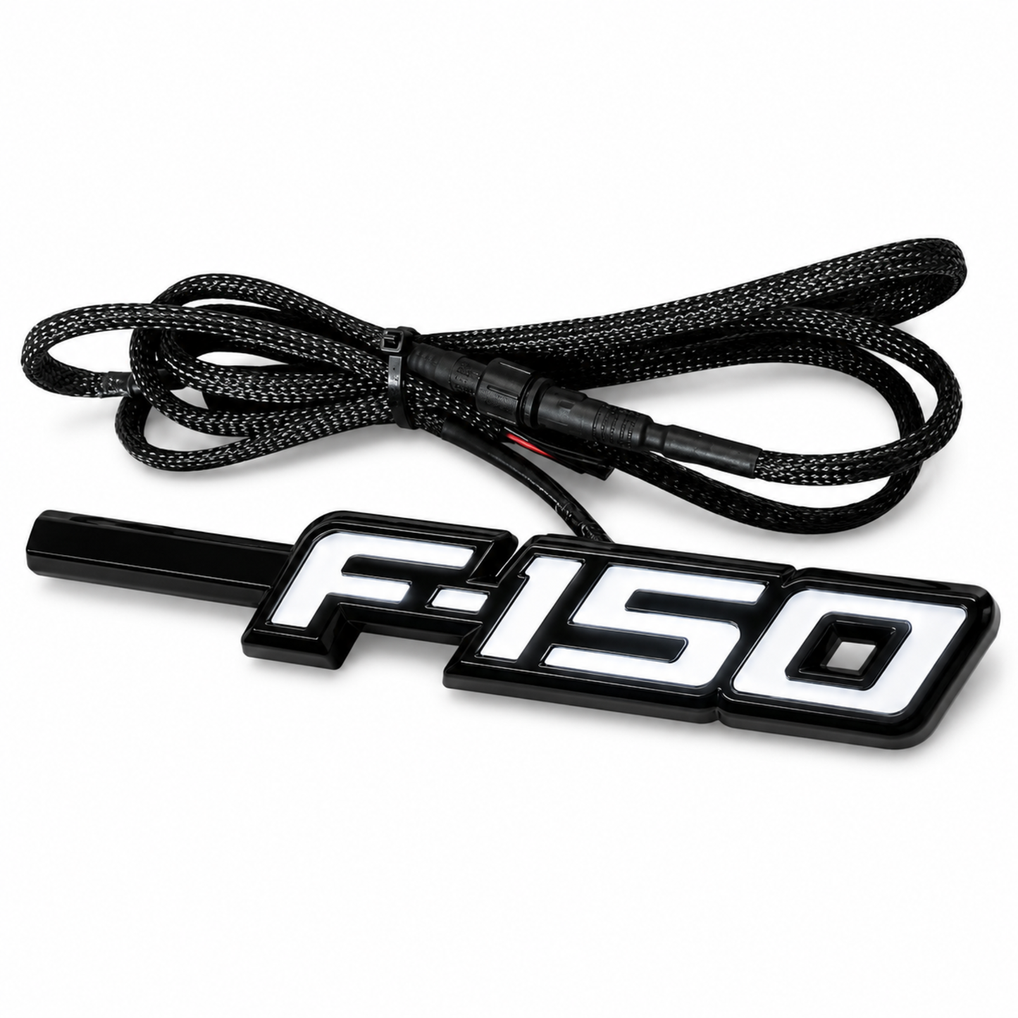 Angled view of Ford F-150 LED Fender Emblem for 2009-2014 models with black and chrome housing, white LED illumination, and integrated wiring harness.