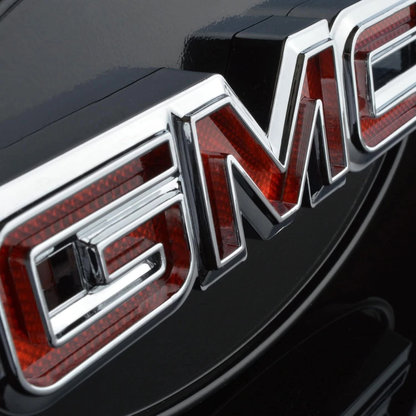 Close-up detail of chrome GMC lettering on LED hitch receiver cover showing red lens texture