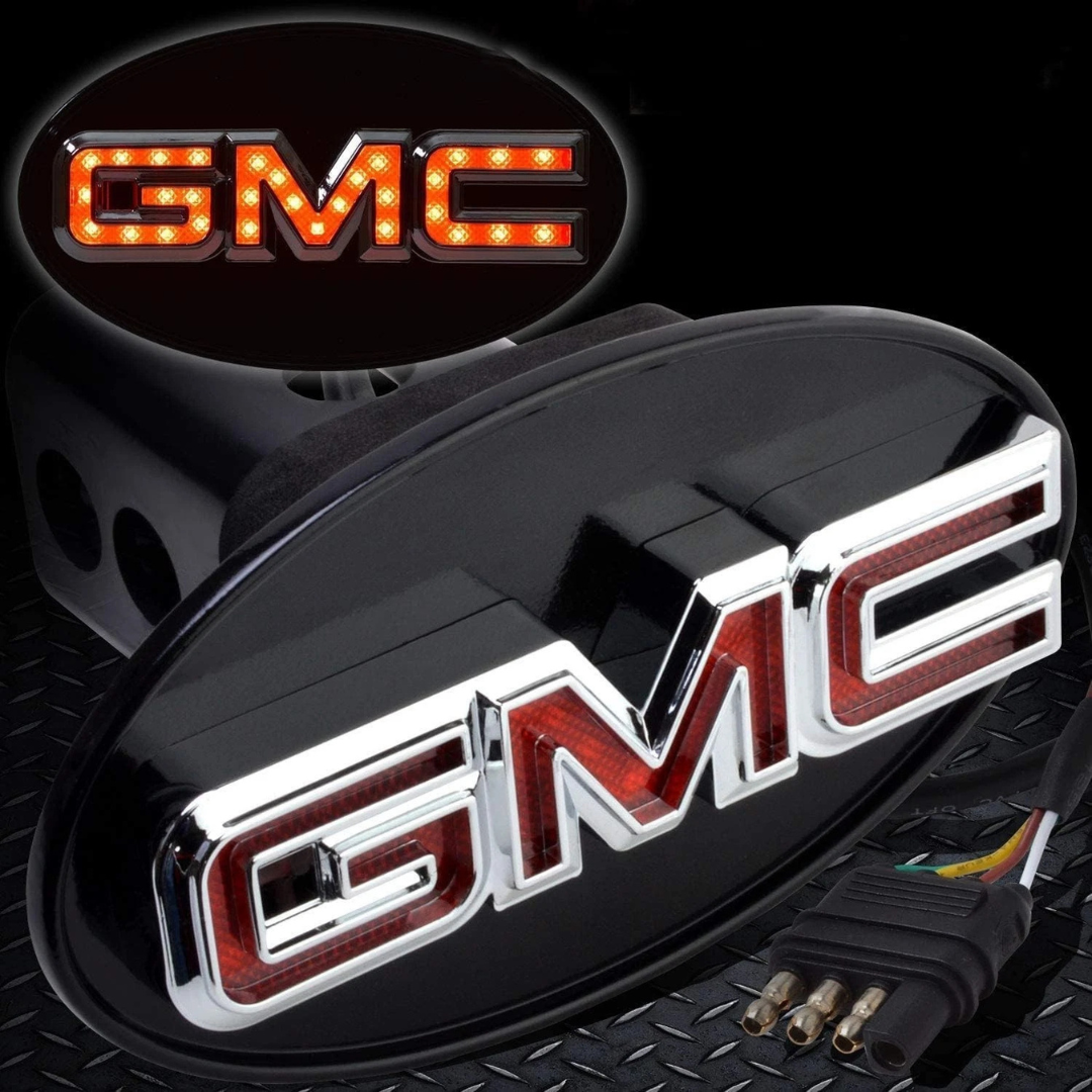 Chrome GMC LED hitch receiver cover illuminated with red LEDs showing running light brightness and 4-way trailer plug connector