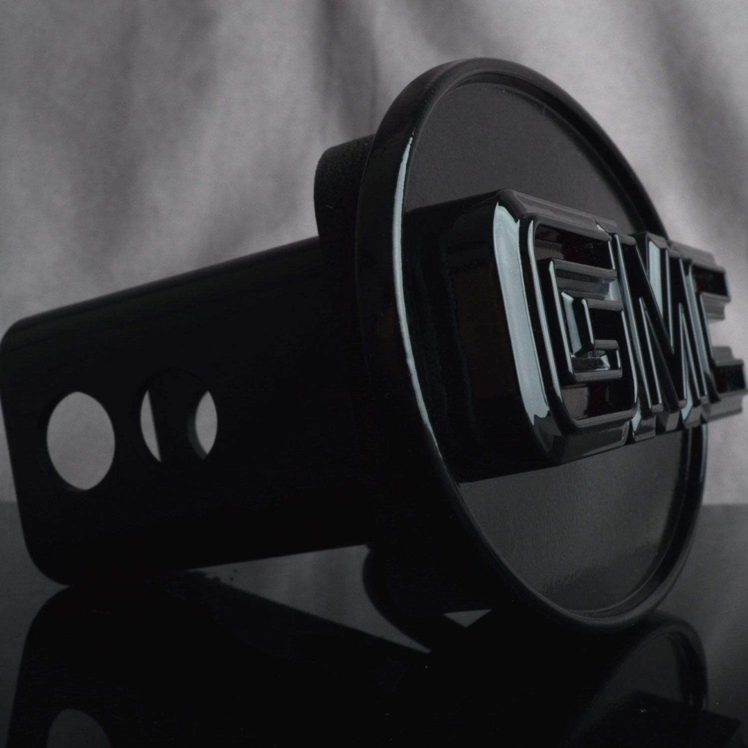 Angled view of gloss black GMC LED hitch cover showing raised lettering and receiver mount housing