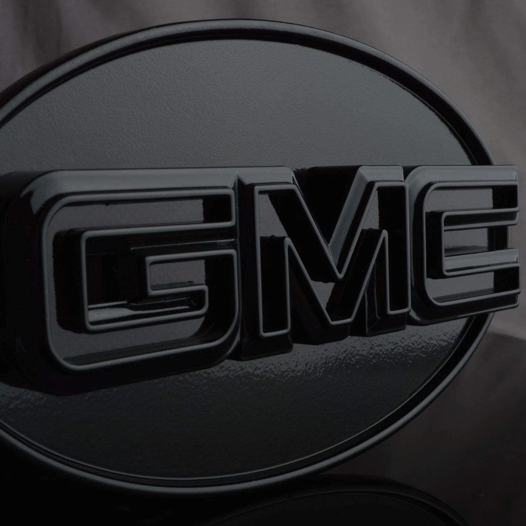 Close-up front view of gloss black GMC LED hitch cover highlighting raised GMC lettering and smooth finish