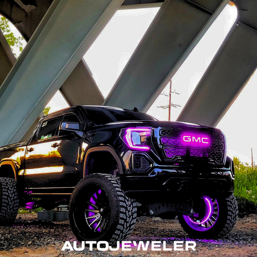 AutoJeweler GMC illuminated grille emblem glowing purple on lifted truck
