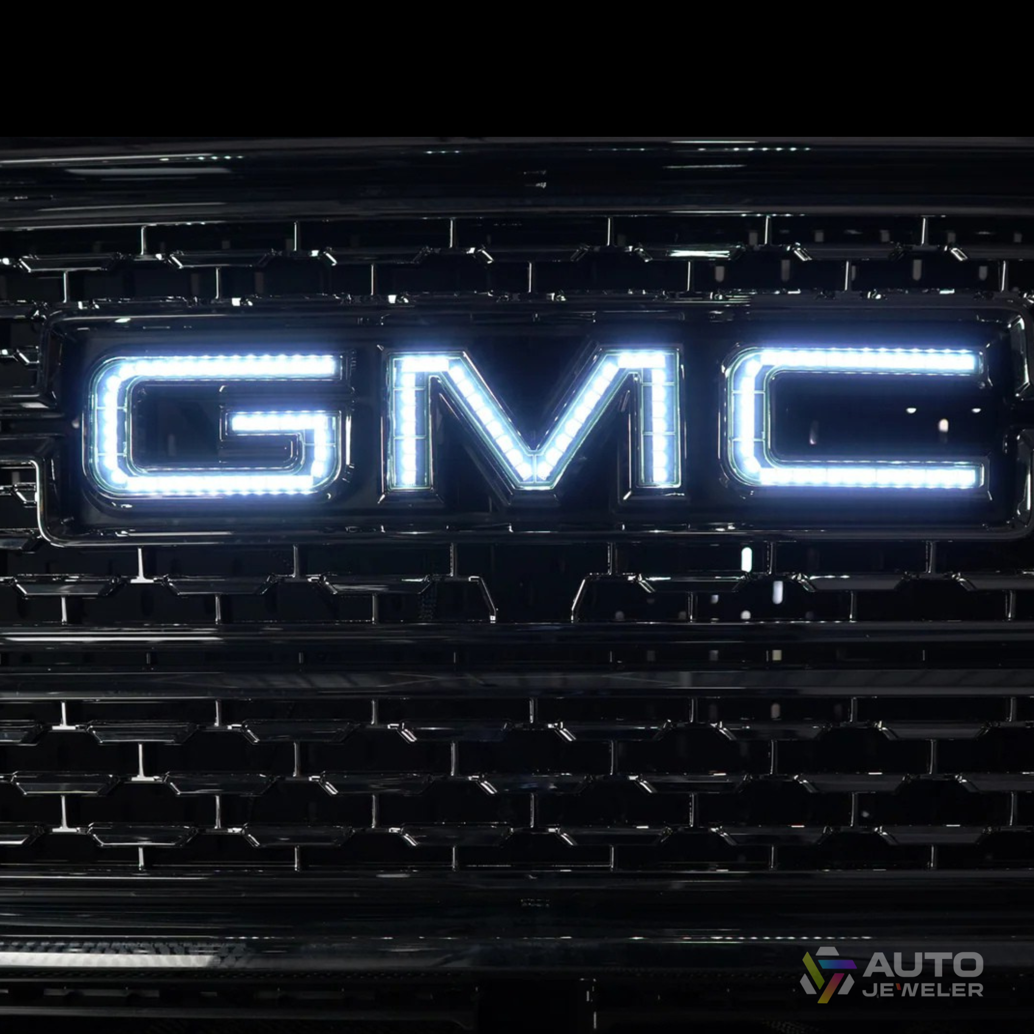 AutoJeweler white RGBW GMC LED illuminated grille logo showing bright pure white output on a GMC Sierra front grille.