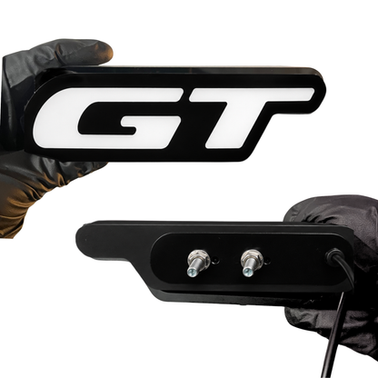 GT Flow Series RGB LED grille badge front and back view showing black housing, mounting studs, and wiring for secure custom grille installation.