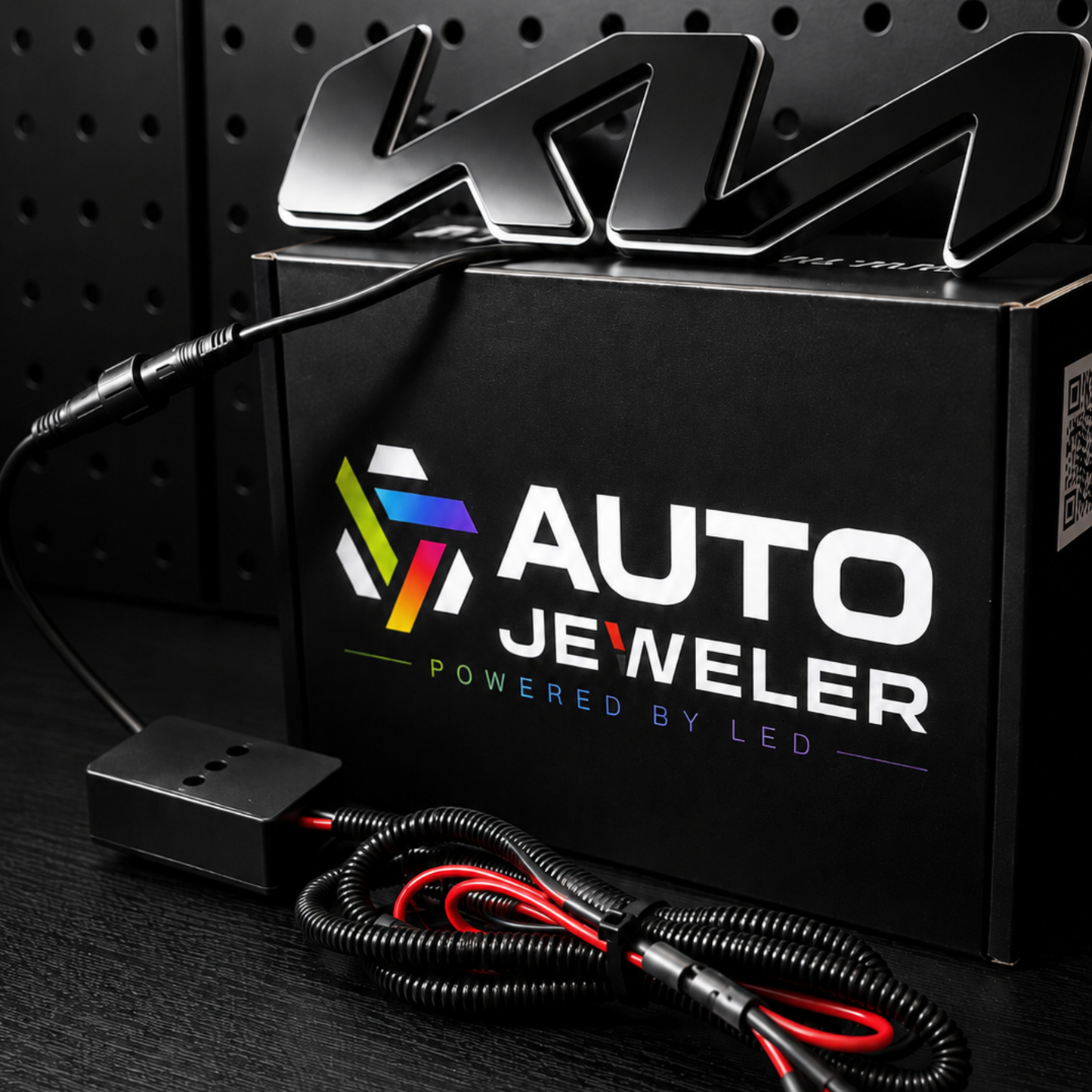 Auto Jeweler powered by LED light bar kit with its black retail box, wiring harness, and a large black metallic K22 emblem on a dark textured background.