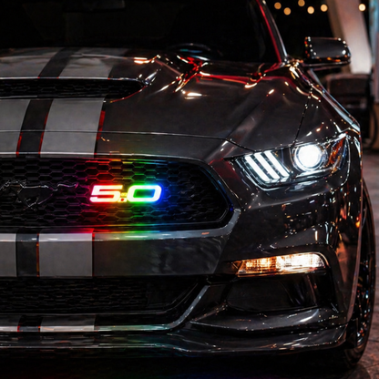 Ford Mustang front grille with 5.0 RGB Flow Series LED emblem installed showing rainbow color flow lighting at night