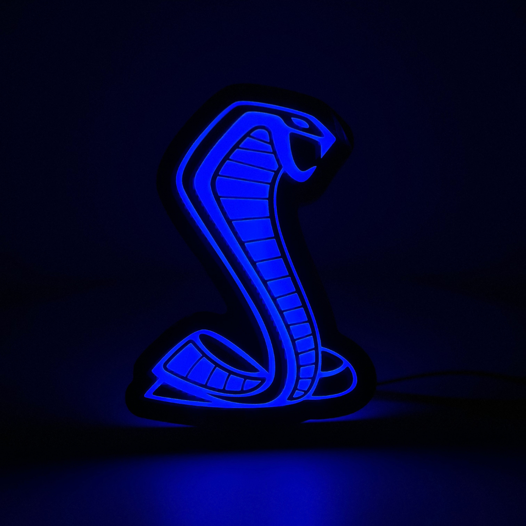 Mustang Cobra RGBW grille emblem glowing solid blue in a dark environment, showcasing LED brightness and vivid illumination

