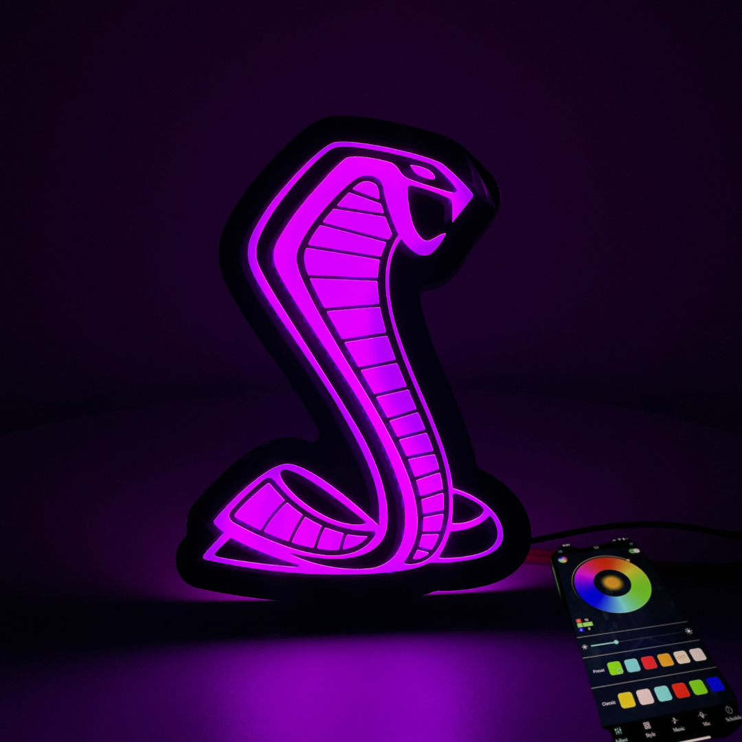 Mustang Cobra RGBW grille emblem illuminated in purple with Bluetooth app controller display showing color wheel and effect settings