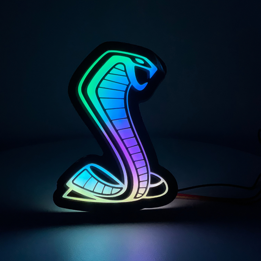 Mustang Cobra RGBW grille emblem glowing in flow mode with multicolor night display, showing full-spectrum LED transition effect