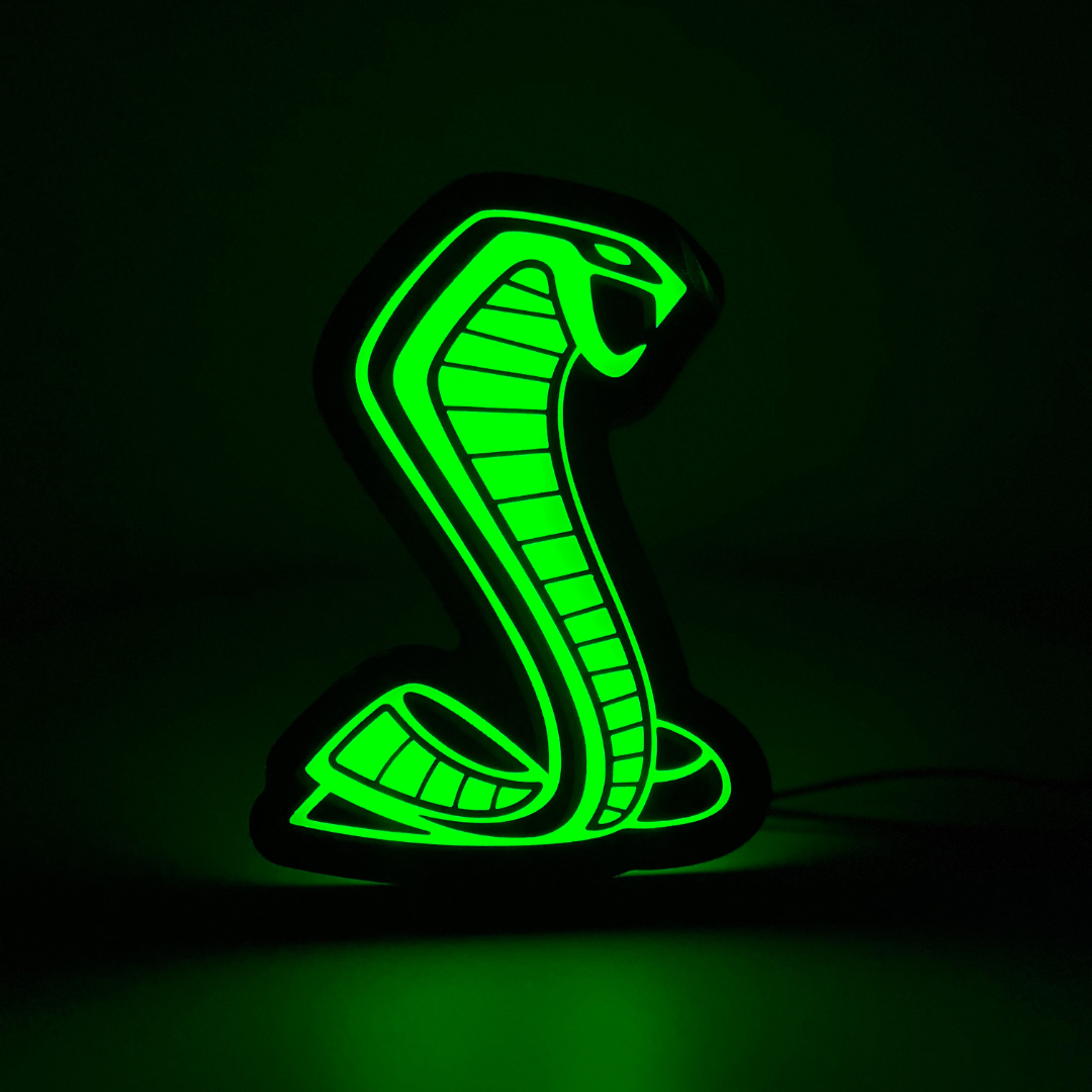 Mustang Cobra RGBW grille emblem glowing solid green in a dark environment, showcasing LED brightness and vivid illumination

