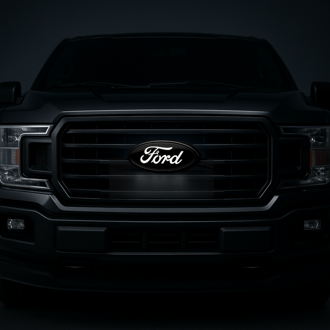 AutoJeweler 9-inch Ford LED grille emblem in gloss black; letters illuminate white. Kit contents and installation shown on turntable.