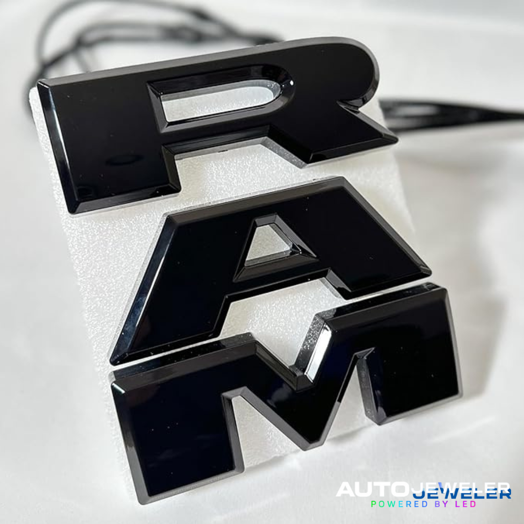 Close-up of RAM 1500 black RGB LED lighted grille emblem, glossy finish, AutoJeweler Powered by LED branding