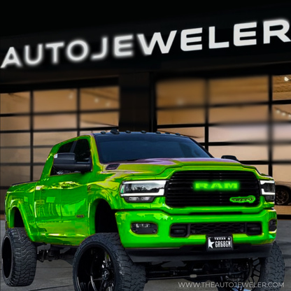 Lifted green RAM 2500 truck with green LED grille emblem parked in front of AUTOJEWELER storefront, custom license plate visible.