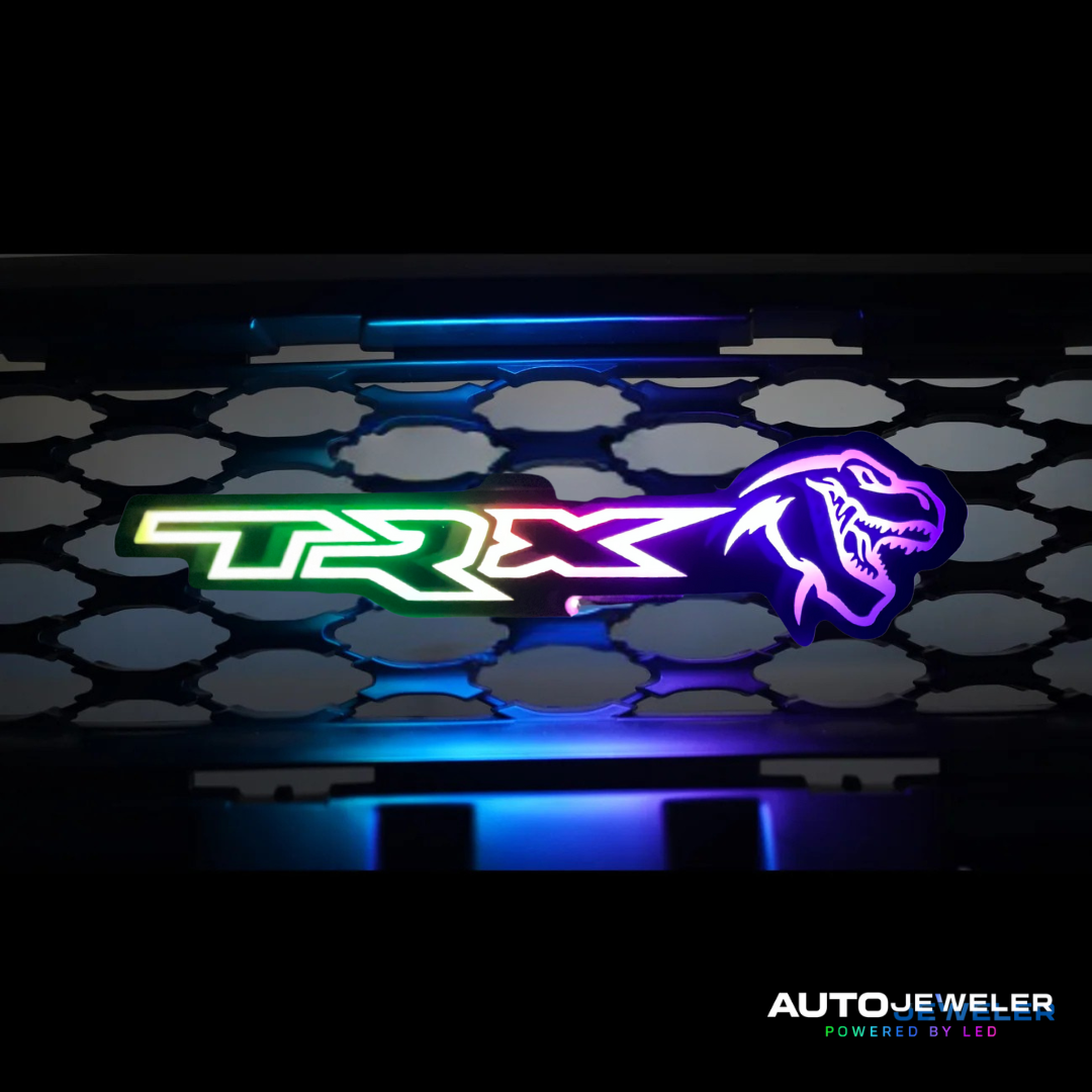 Neon TRX logo installed on a truck grille with 'AutoJeweler' branding.