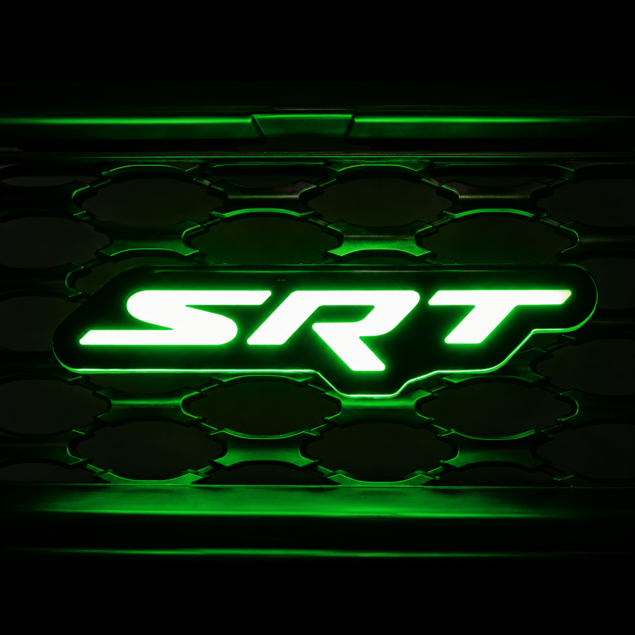 SRT LED grille emblem installed on black grille illuminated in green with matching green glow and grille reflections.