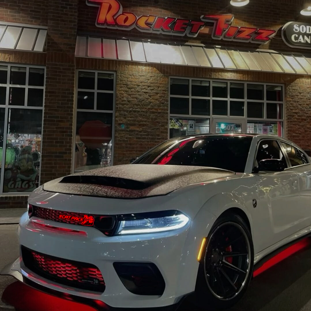 White Dodge Charger with red underglow and grille lighting with an installed ScatPack Color RGB LED Flow-Series Grille emblem with a matching bright red glow in front of Rocket Fizz
